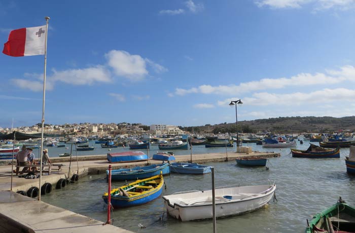 Vista del puerto de Marsaxlokk y un grupo de pescadores charlando